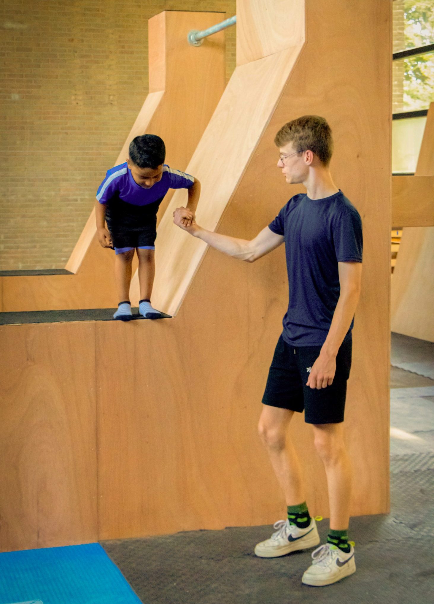 Professionele trainer helpt met Freerunsprong van obstakel bij Freerunworkshop!